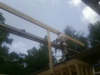 Carpenter setting a ridge beam over a new addition frame — Ice Dam Removal by Roofing Brothers in Cogan Station