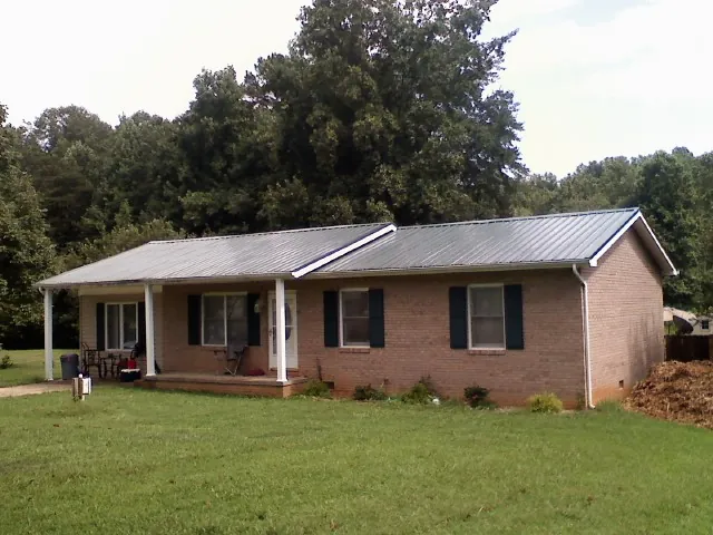 Gray metal roof on a brick ranch house with a side carport in Cogan Station