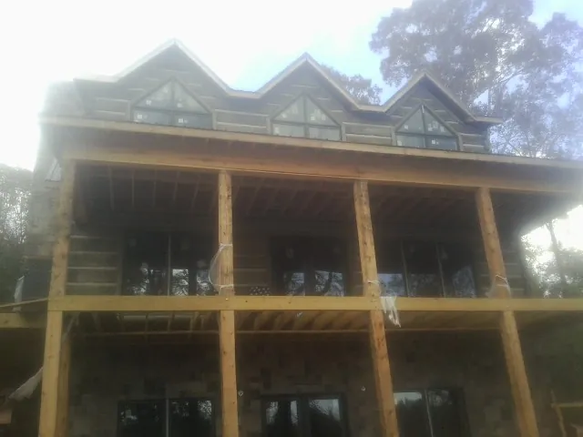 Dormers and porch framing on a large log home under construction — Roof Coating work by our crew in Cogan Station