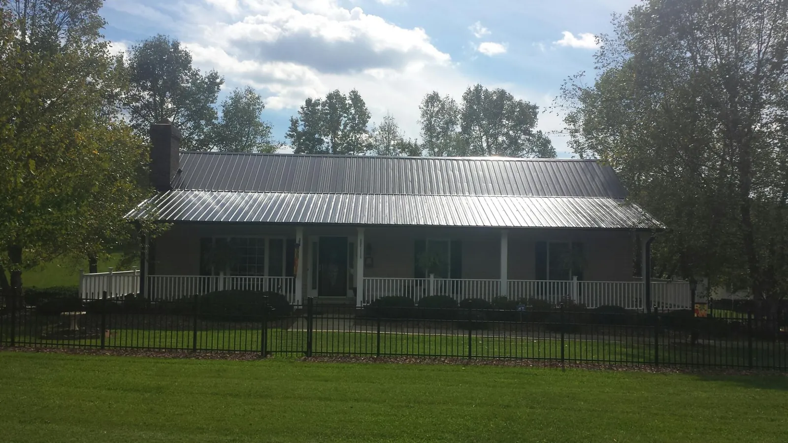 Gray metal roof on a brick ranch with a full width front porch — Gutter Guard Installation work by our crew in Cogan Station