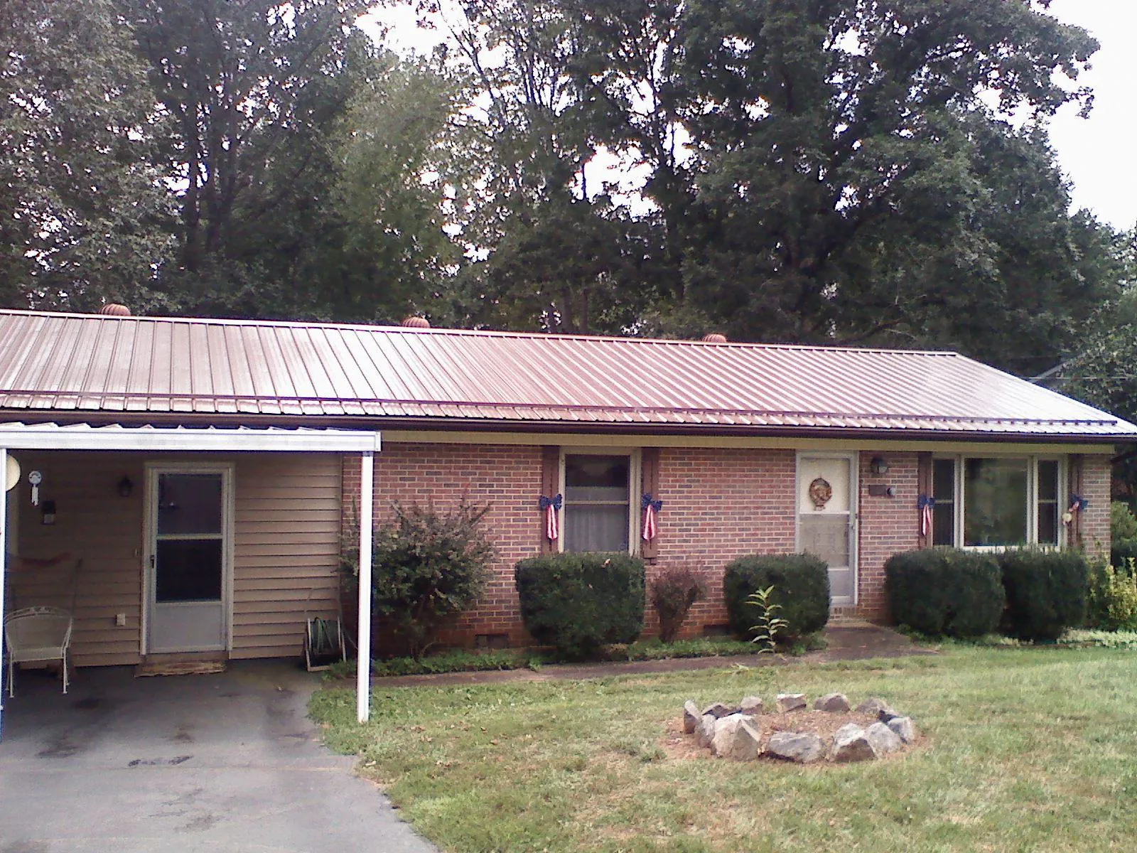 Bronze metal roof and carport on a brick ranch home — Roof Repair work by our crew in Cogan Station