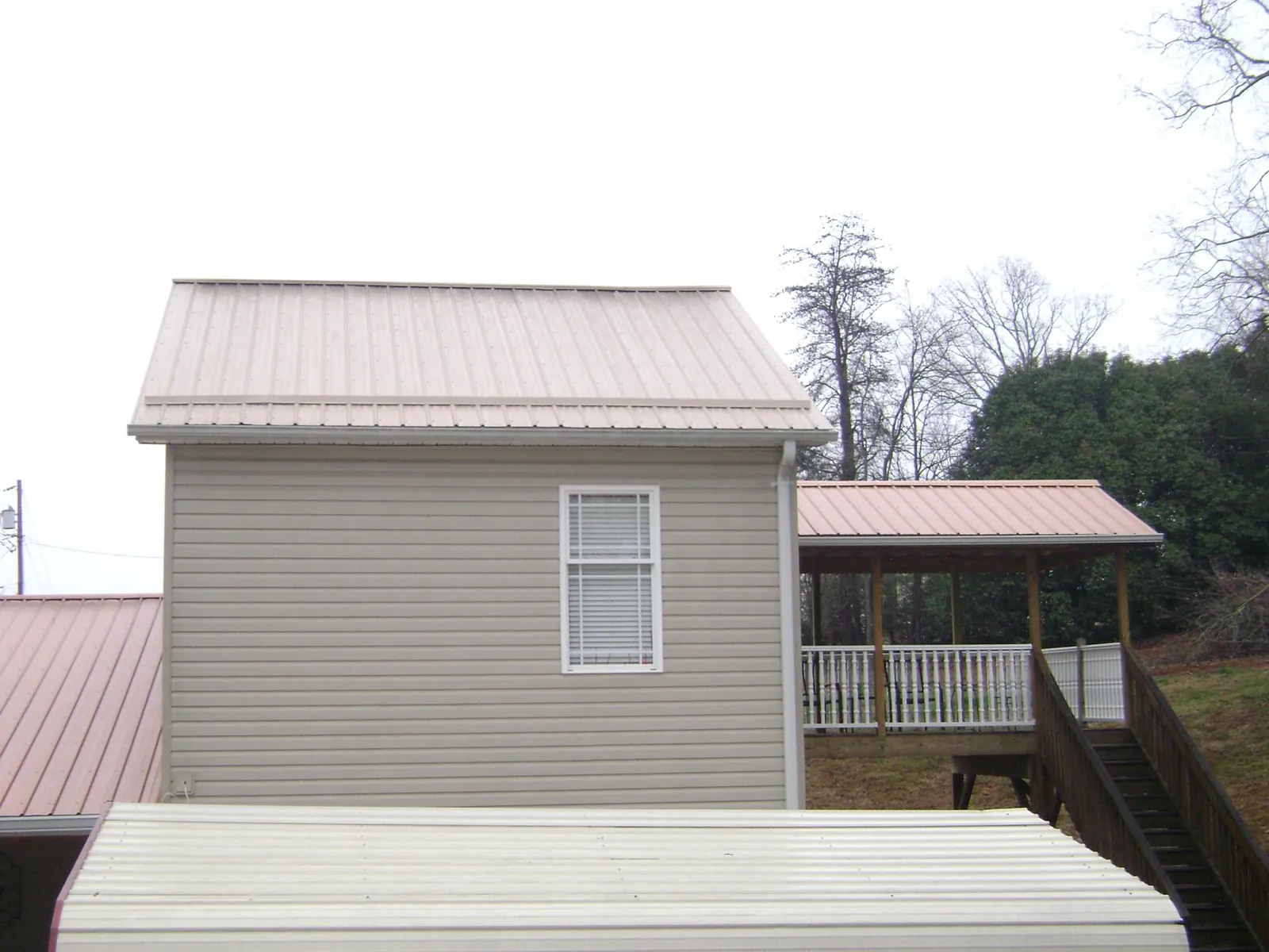 Tan metal roofs on a two story addition and attached porch, from a Roof Replacement job in Cogan Station