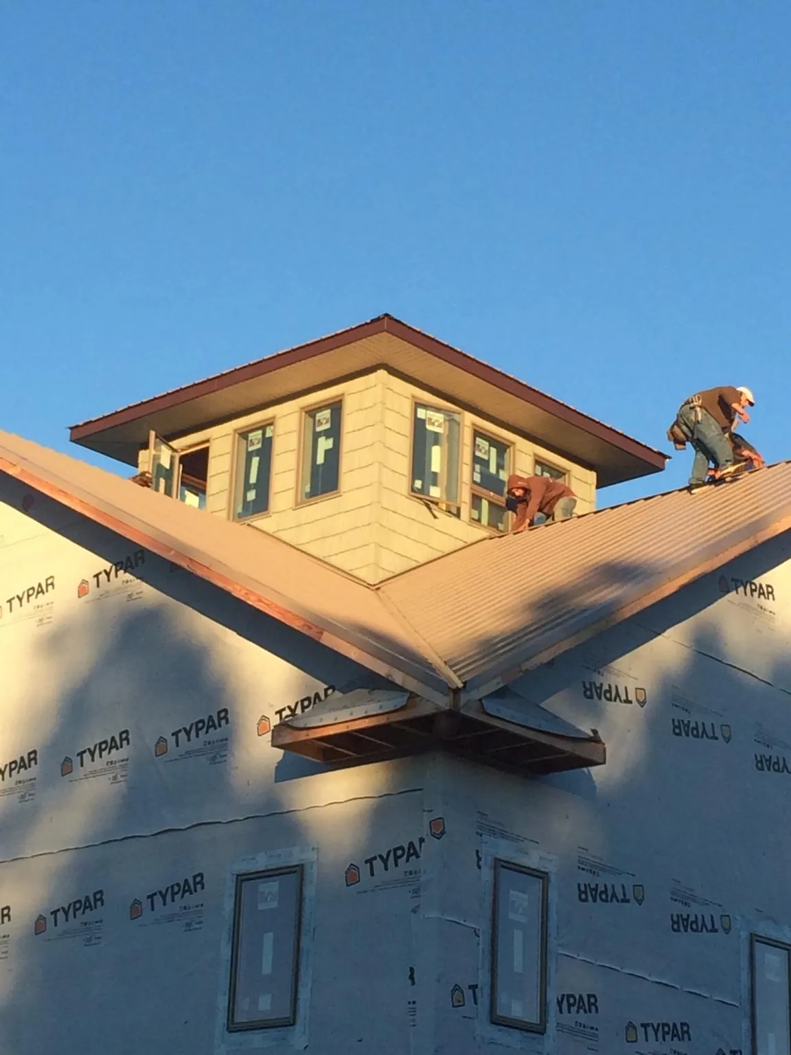 Roofers working around a rooftop cupola on a new metal roof at sunset — Roof Waterproofing in Cogan Station by Roofing Brothers